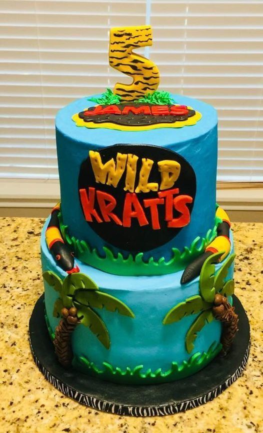 Wild Kratts themed blue birthday cake with a large yellow “5” topper and animal decorations