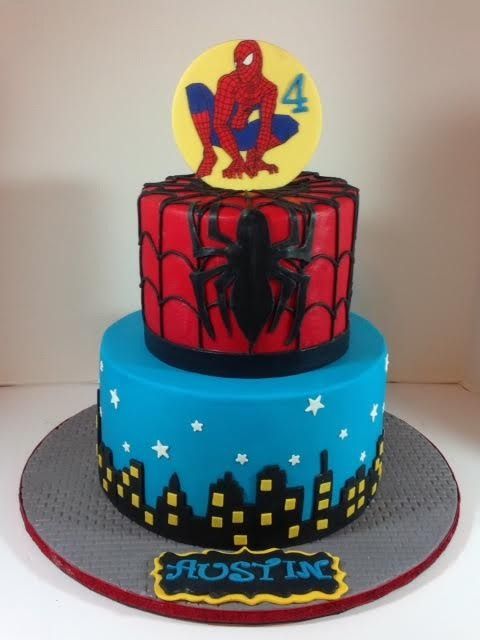 Spider-Man birthday cake with red-and-blue topper and blue base featuring city buildings and the name “Austin”