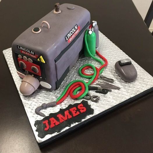 Custom cake decorated as a gray machine with green hoses and red detailing, labeled