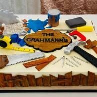Assorted woodworking tools and materials around a wooden sign reading “The Grahmann’s” on a worktable