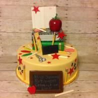 Yellow decorated cake with red stars, a red apple topper, and a small chalkboard sign