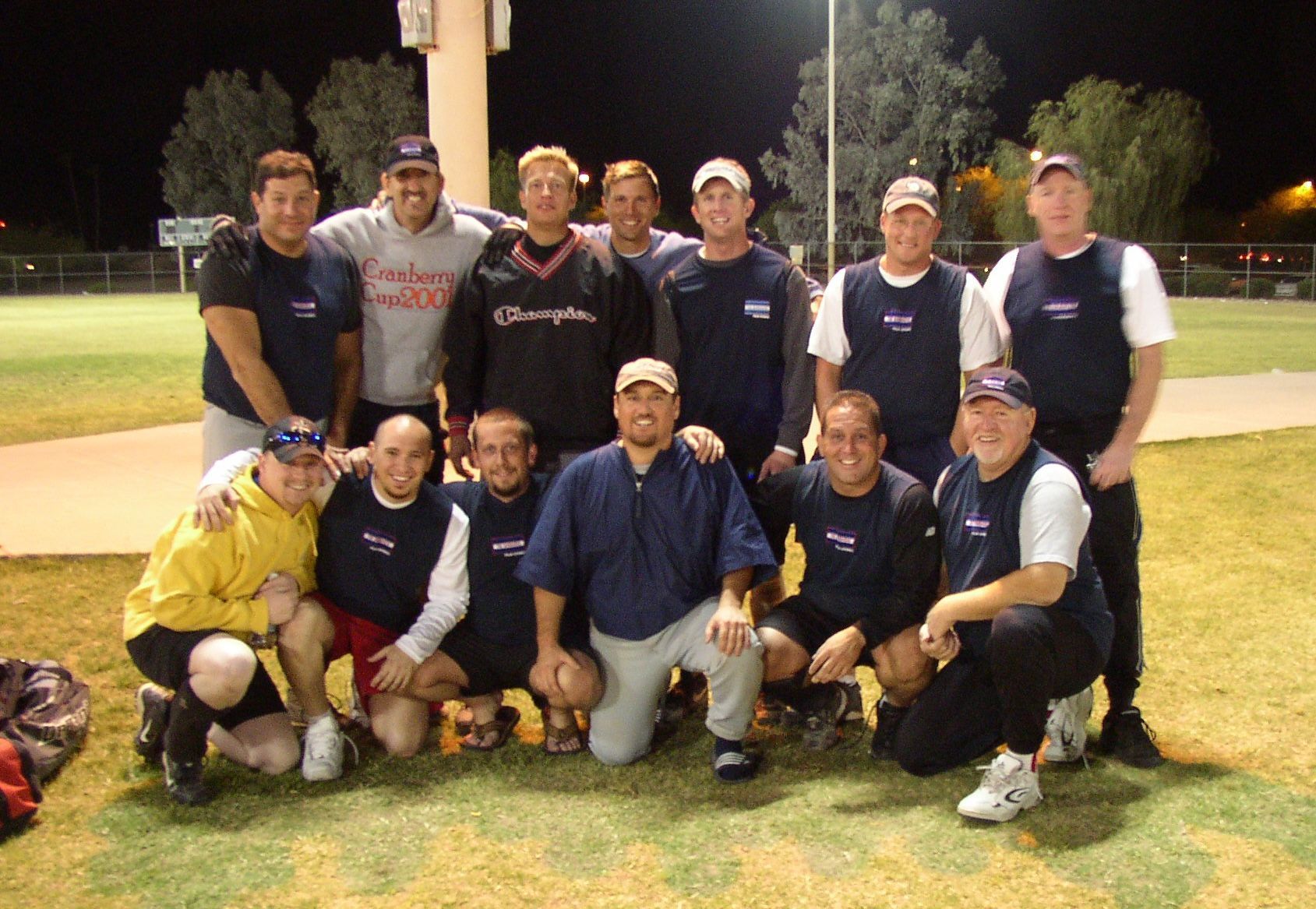 Group of six people in matching black shirts posing together at an indoor event.