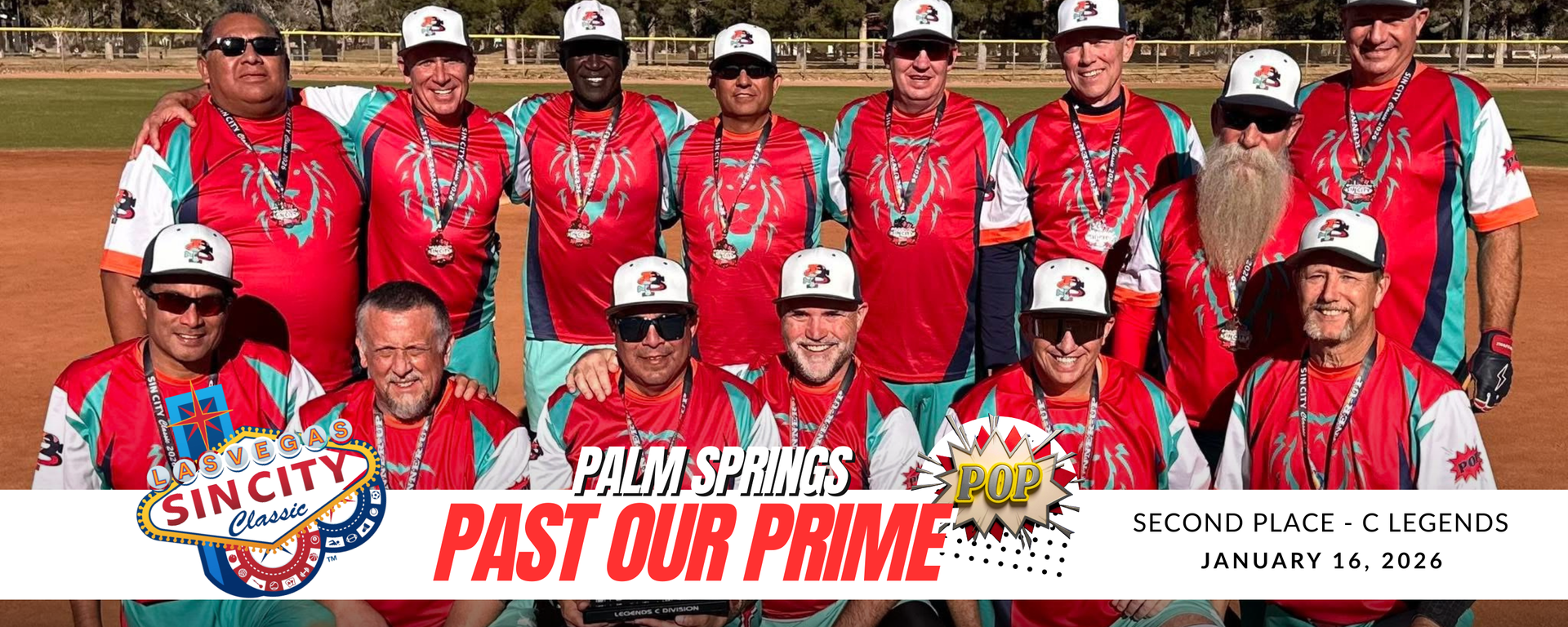 Baseball team in red jerseys posing with a championship banner and trophy on a field