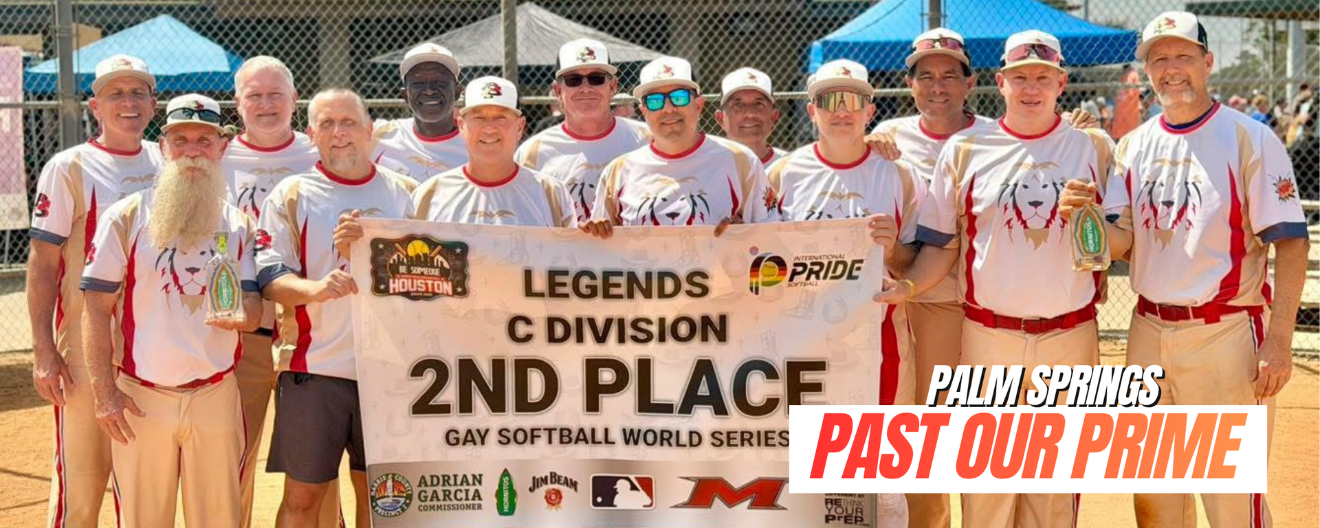 Softball team posing with a “2ND PLACE” banner and “Past Our Prime” text at a dusty field
