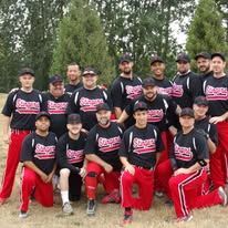 Group of baseball players in black jerseys and red pants posing outdoors with bats and gloves