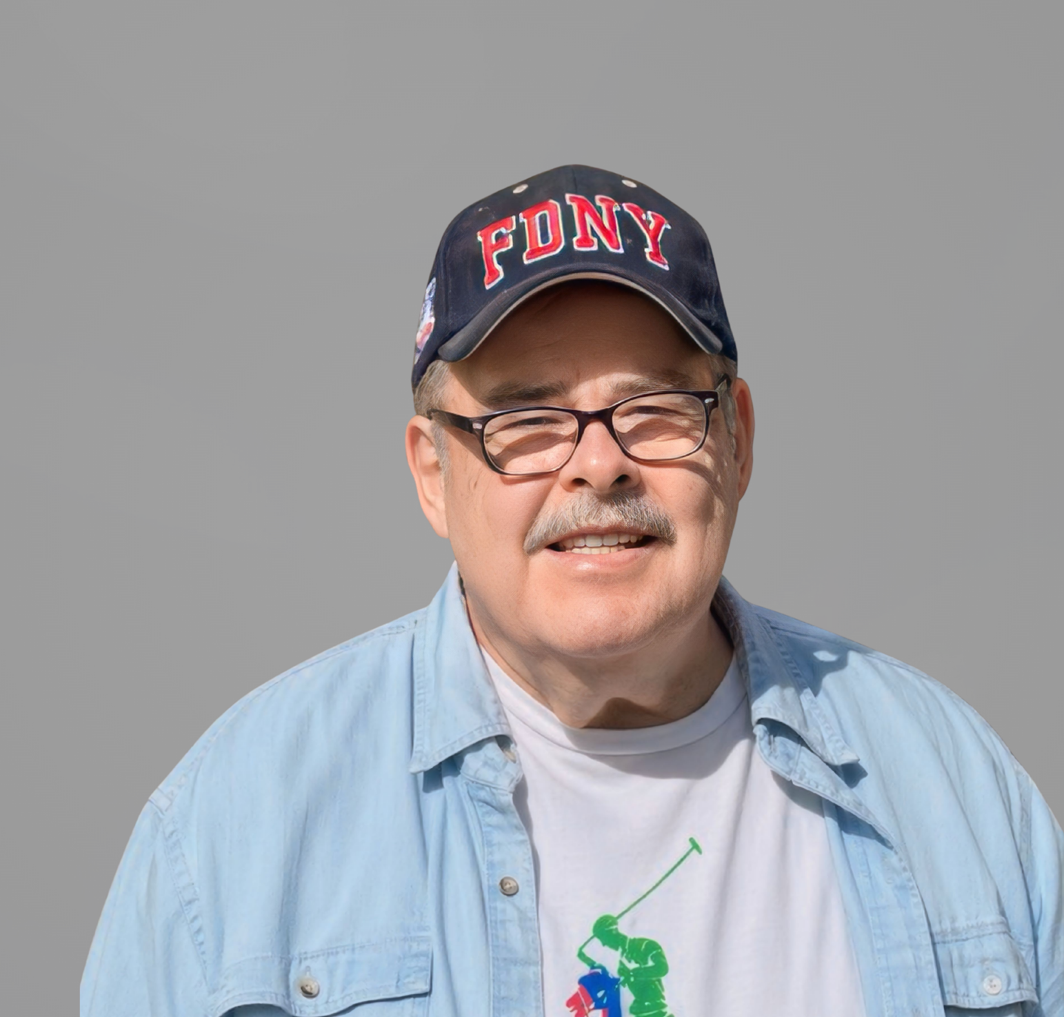 Man wearing a navy FONY cap, glasses, and a light blue shirt, smiling against a gray background
