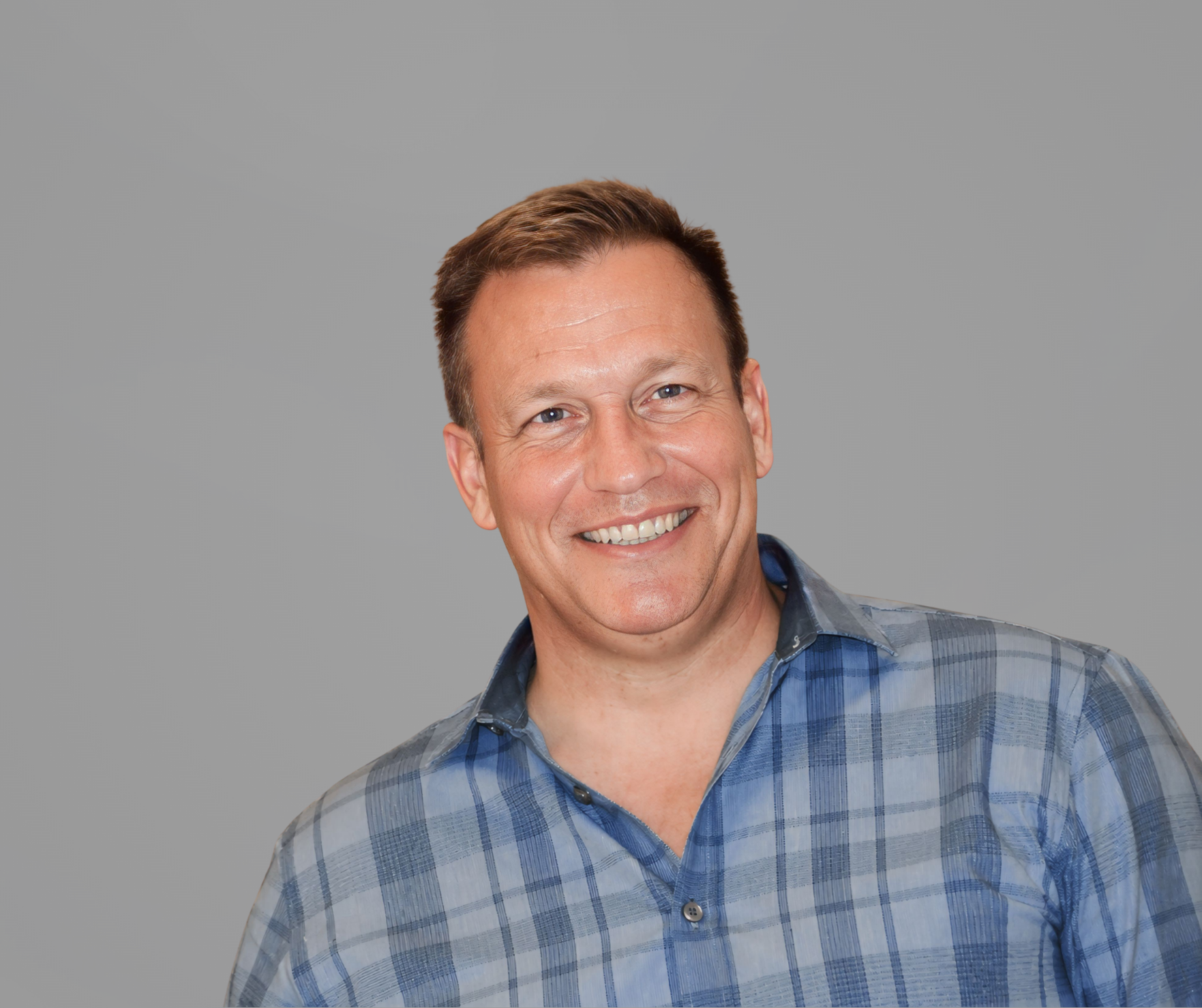 Headshot of Ross Benson, a man smiling, wearing a gray collared shirt, set upon a gray background.