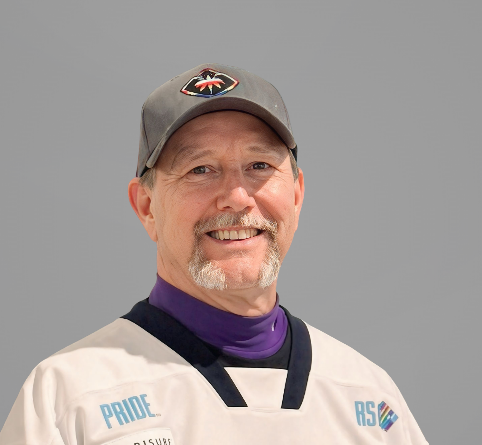 Smiling person in a white jersey and gray cap against a gray background.