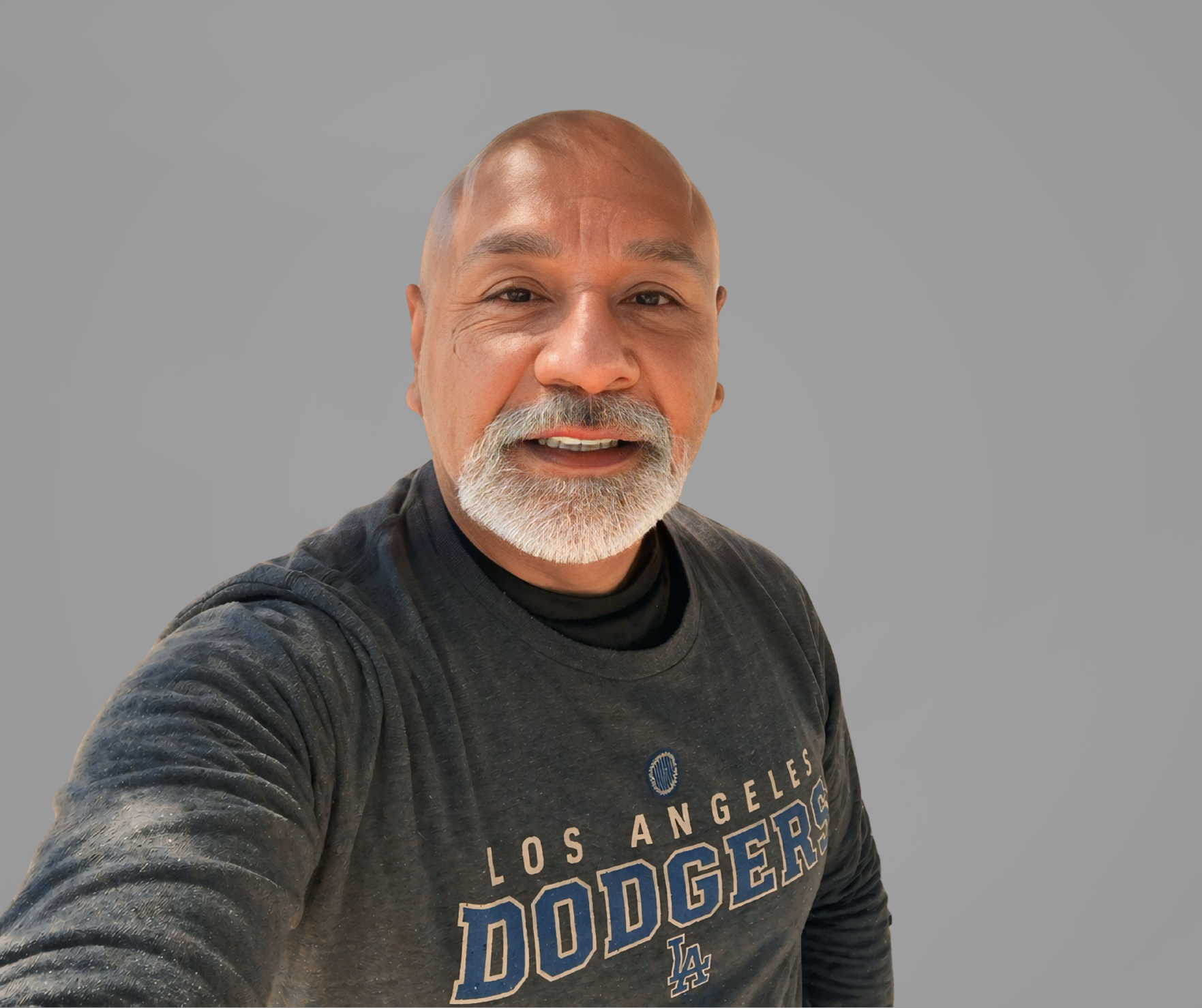 Headshot of Martin Juarez, a man smiling, with a trimmed goatee, wearing a gray shirt, set upon a gray background.