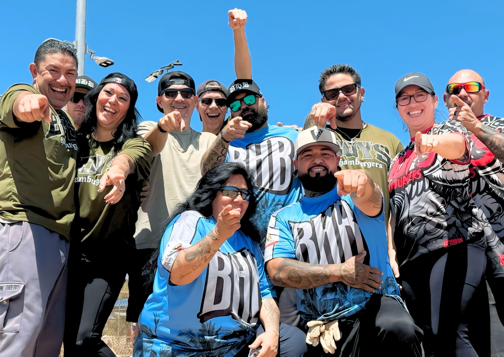 Group of fans in matching blue jerseys cheering outdoors on a sunny day