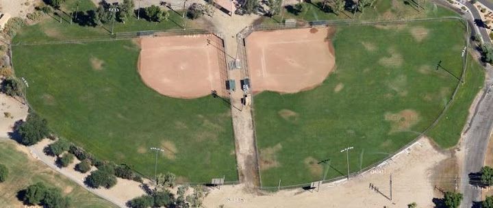 Aerial view of two baseball fields side by side, with green grass and tan infields separated by a central path.
