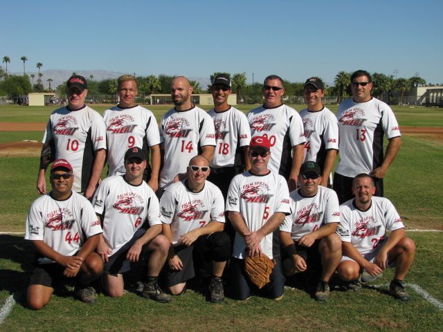 Group of baseball players in white uniforms posing on a field under bright daylight