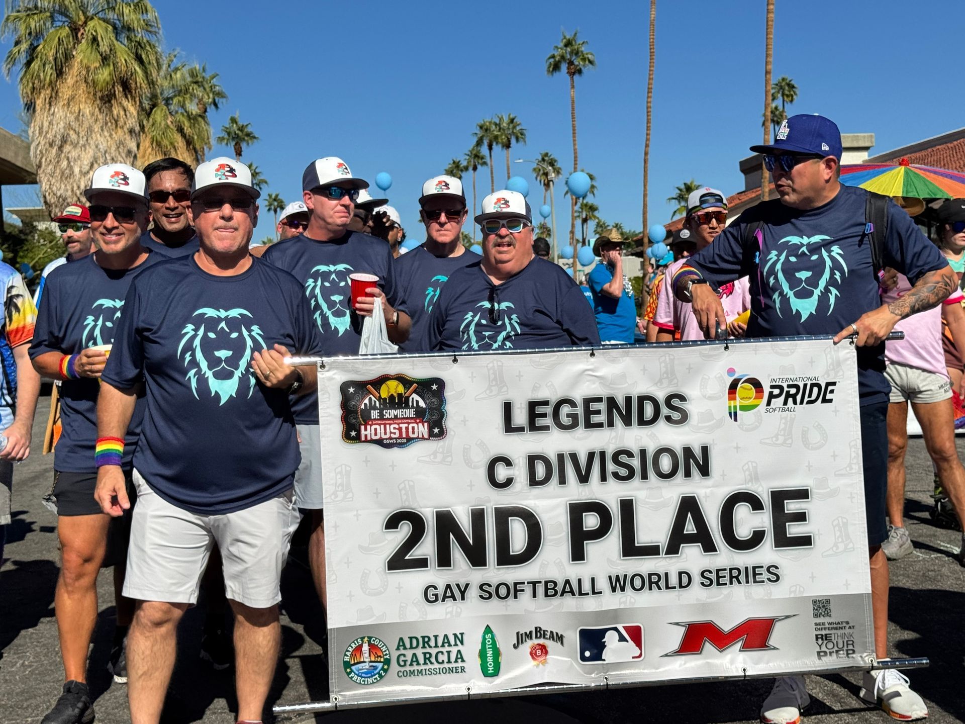 Team holding a banner reading “Legends C Division 2nd Place” at a softball event outdoors.