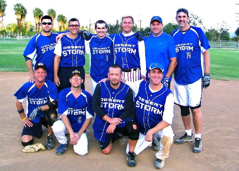 Nine baseball players in blue jerseys pose on a field, two rows smiling for a team photo.