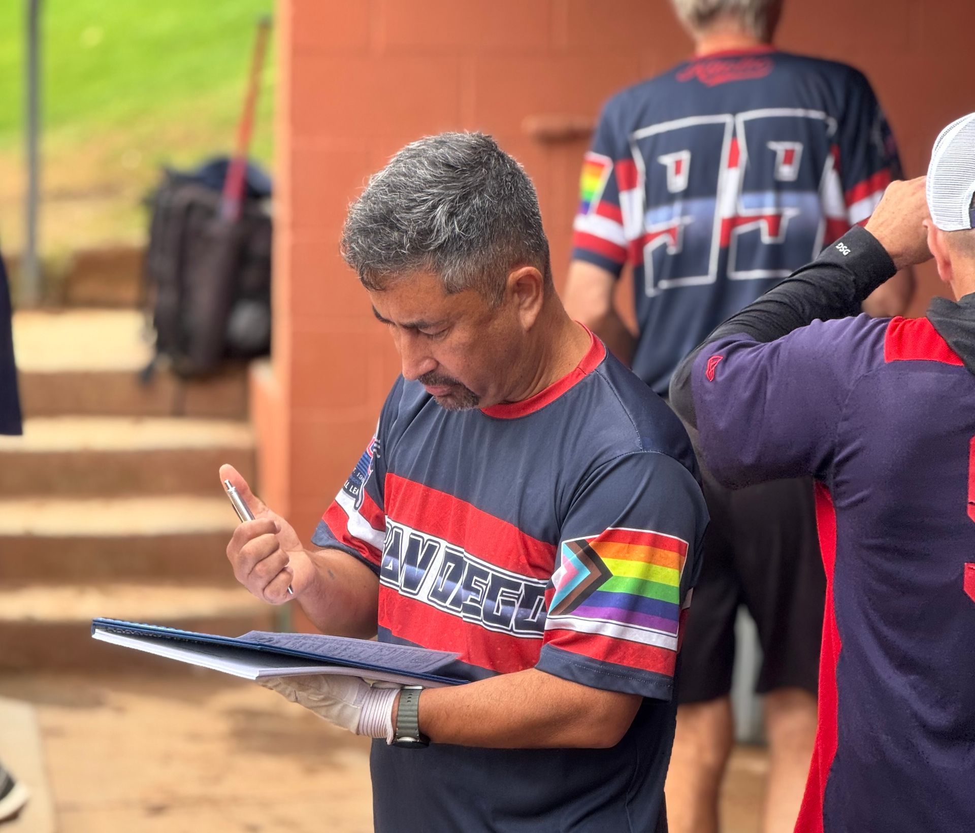 Man in a striped shirt looking at a tablet while standing outdoors among others