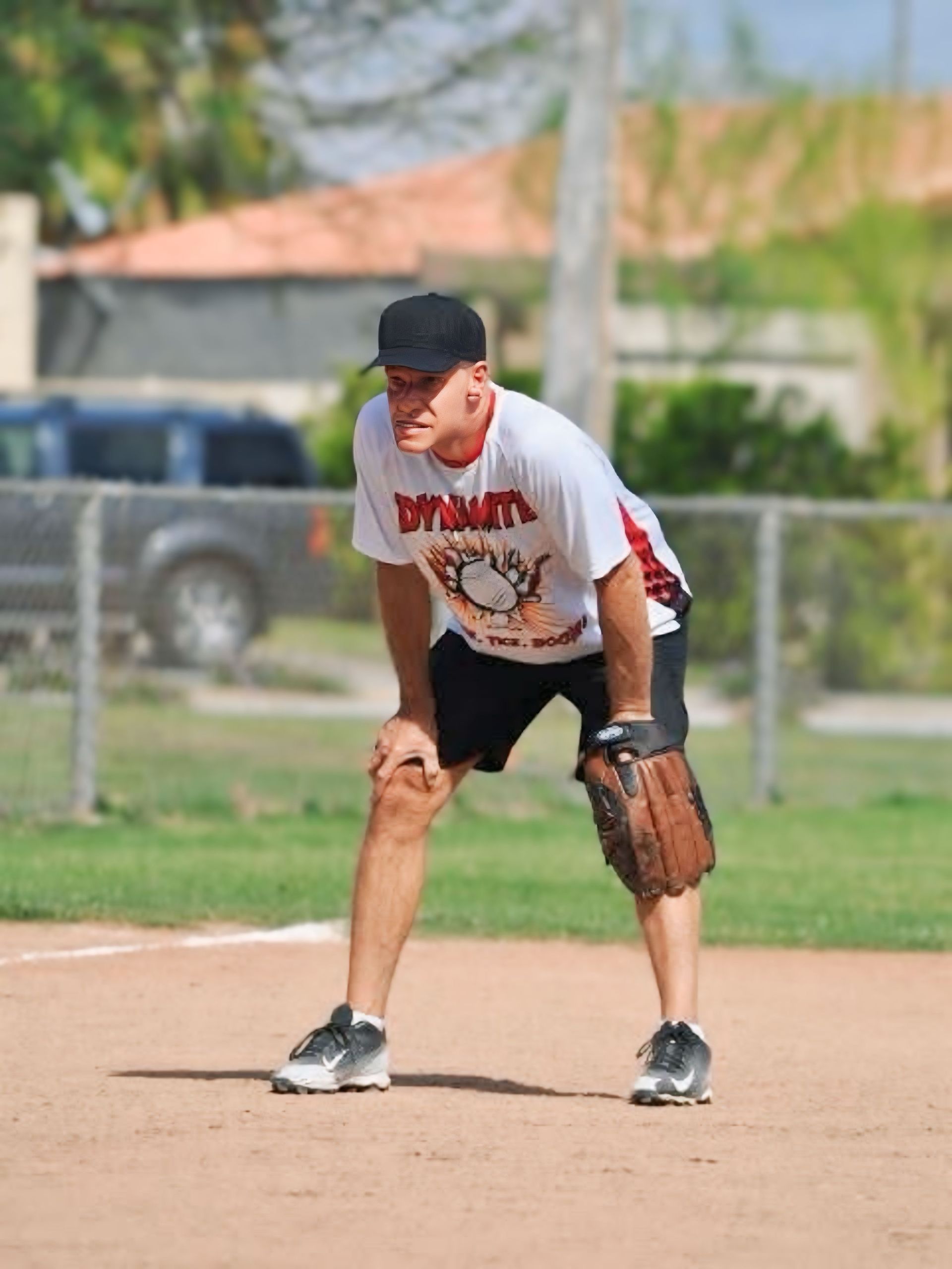 Baseball player in white and black uniform crouching in the infield with a glove, ready for the ball.