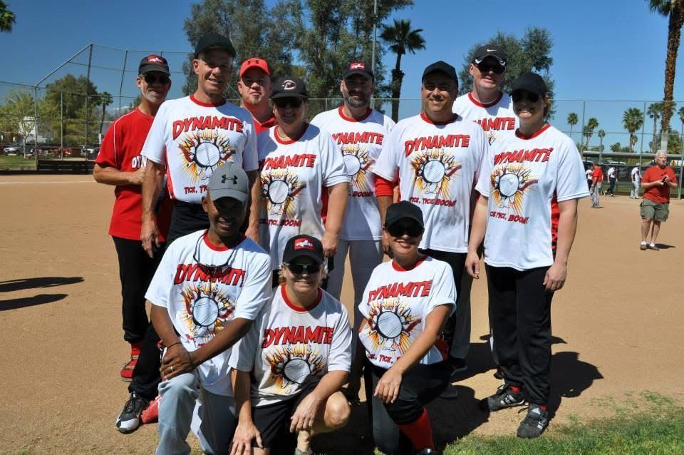 Youth baseball team posing together on a sunny field, wearing matching white jerseys and caps.