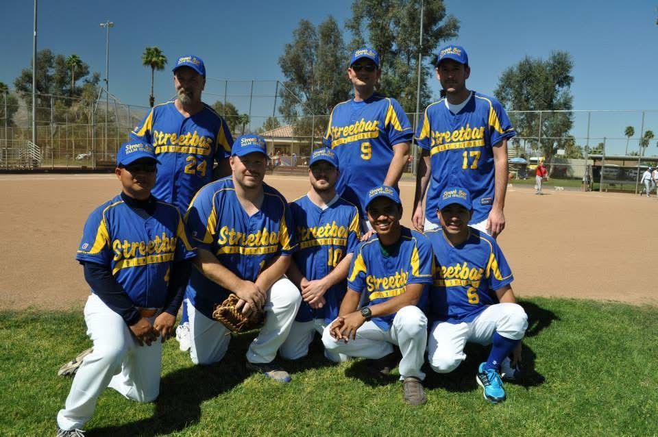 Youth baseball team in blue and yellow uniforms posing on a grassy field.