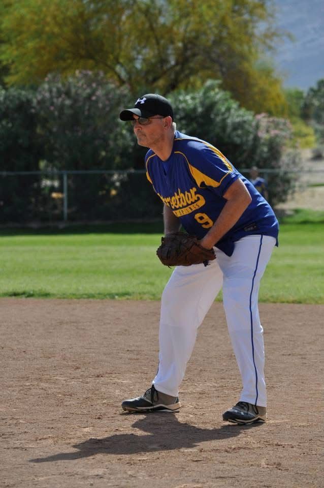 Baseball player in blue and yellow uniform fielding a ground ball on a dirt infield.