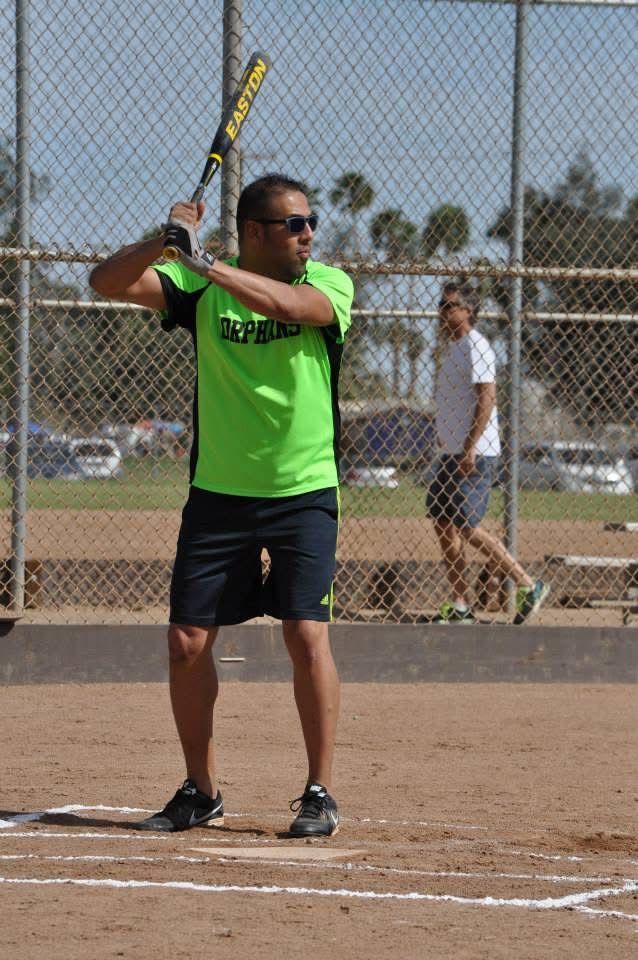 Softball player in neon green shirt holding bat in batting stance on a dirt field