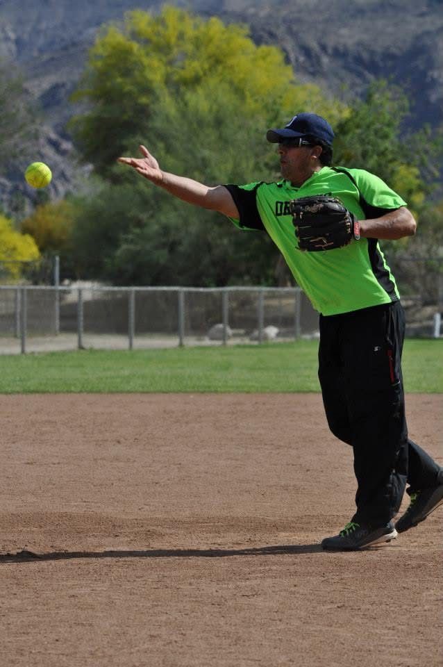 Baseball player in green jersey throwing a ball on a dirt field