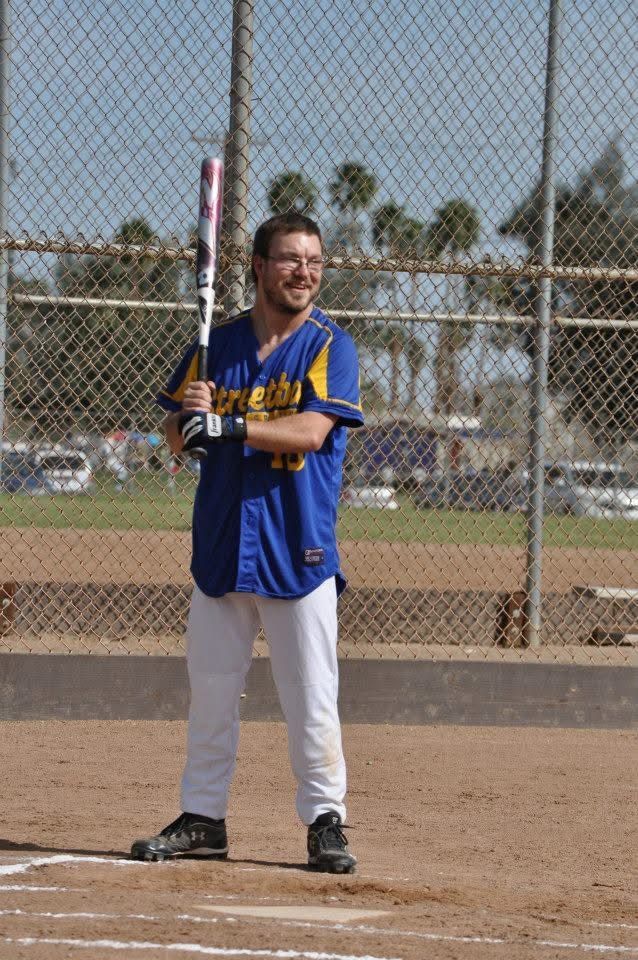 Baseball player in blue jersey holding a bat at home plate on a sunny field