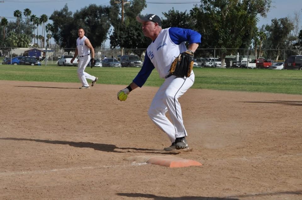 Baseball pitcher in blue and white fielding a ball on a dirt infield during play