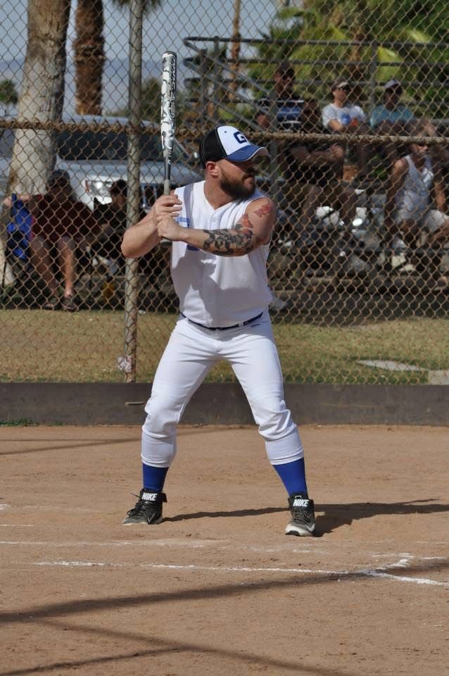 Baseball player in white uniform poised to swing at home plate on a sunny field