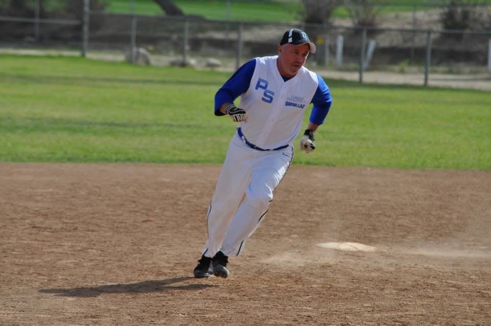Baseball player in white and blue uniform running on a dirt field