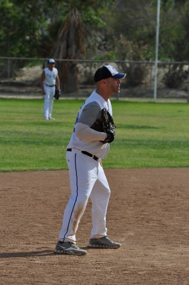 Baseball player in white and gray uniform standing ready on the infield, with another player in the outfield.