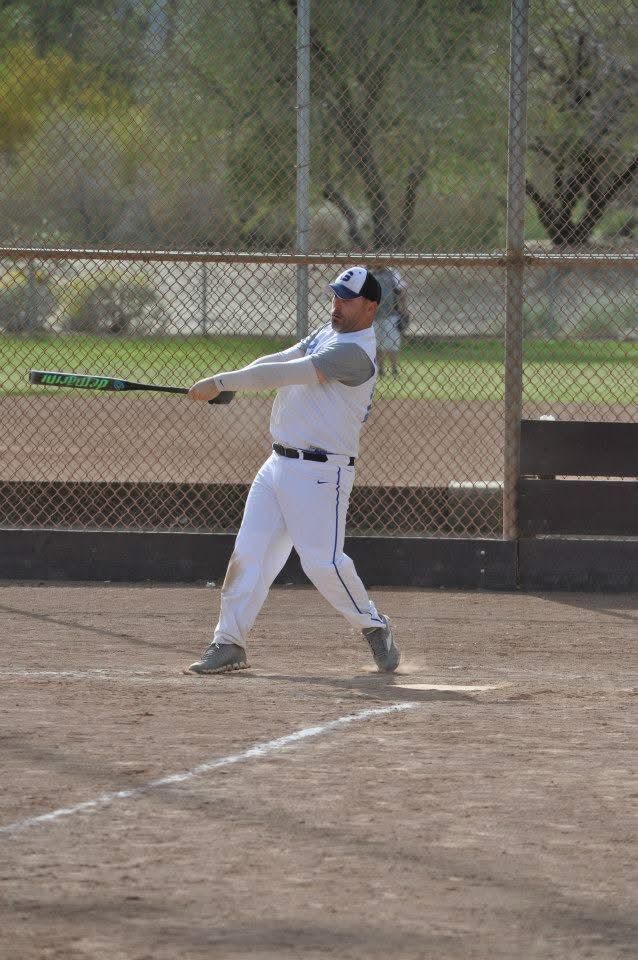 Baseball player in white uniform swinging a bat at home plate on a dirt field.