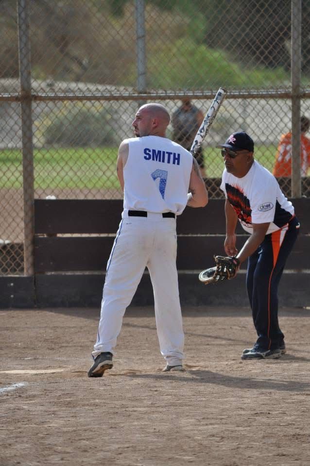 Two softball players on a dirt field, one batting in white with 
