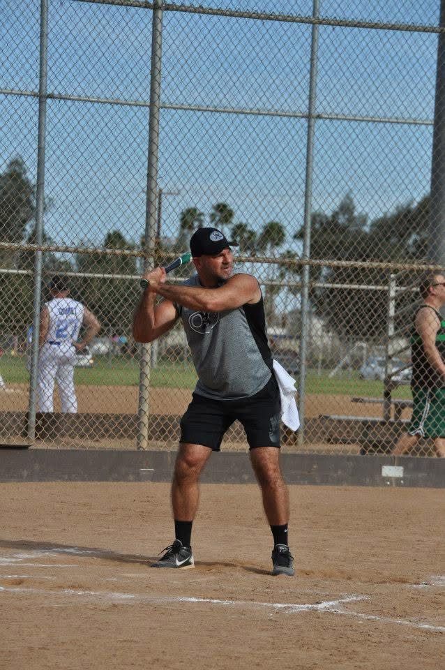 Baseball batter in gray shirt and black shorts poised to swing at home plate