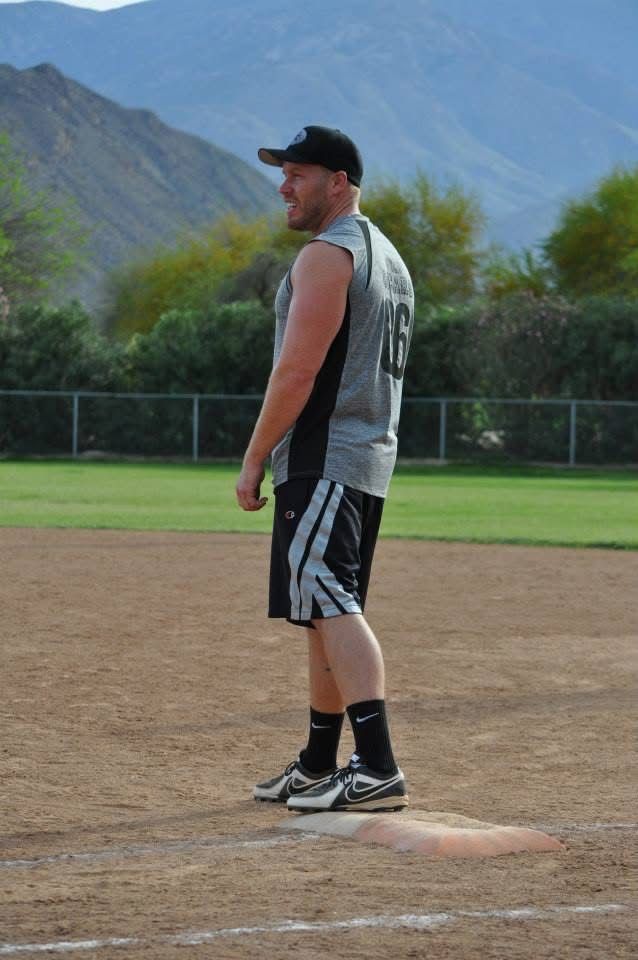 Baseball player in black uniform standing on the pitcher's mound with mountains in the background