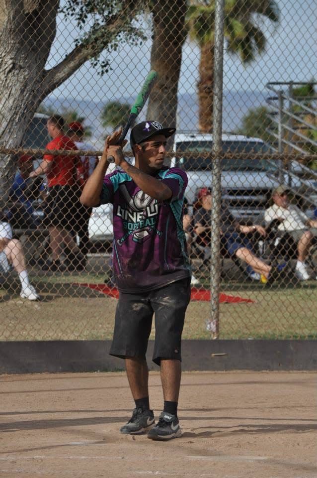 Young baseball player in a purple jersey preparing to swing at home plate on a sunny field