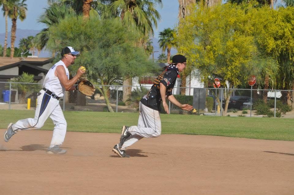 Two baseball players in white and black uniforms sprint across a dirt field during practice.