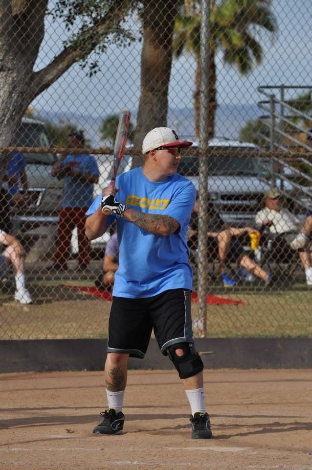Baseball player in blue shirt and helmet preparing to swing on a dirt field