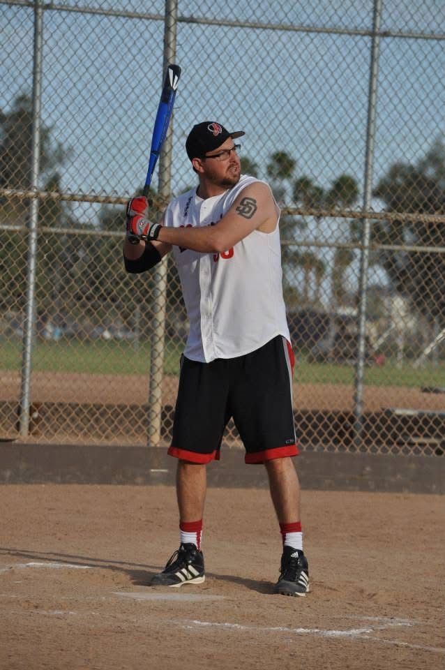 Baseball player at bat on a field, wearing a white jersey and black shorts, ready to swing.