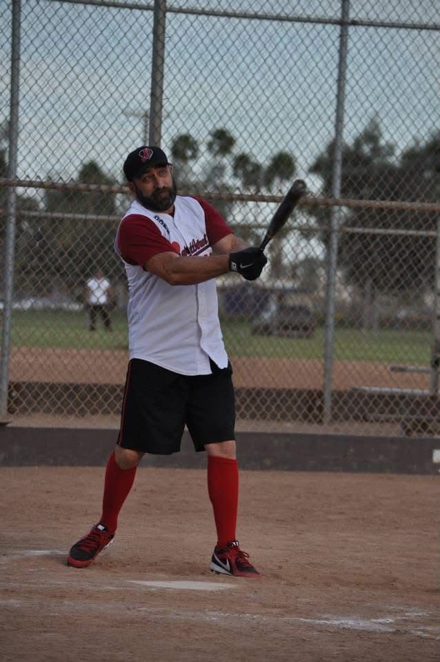 Baseball player in white and red uniform holding a bat at home plate, ready to swing.