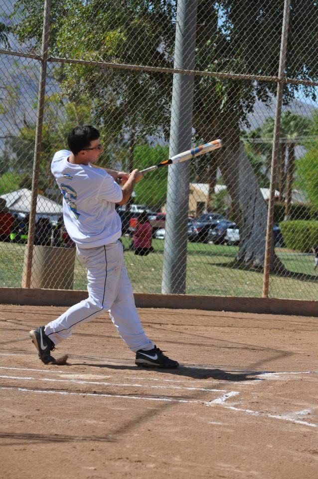 Baseball player in white uniform swinging a bat at home plate during a game