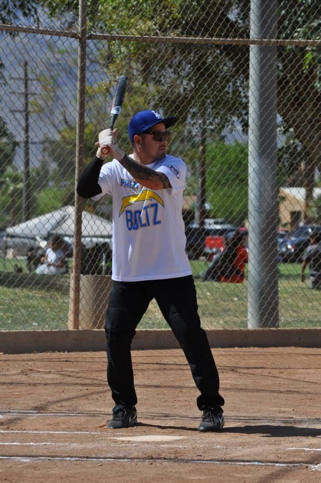 Baseball player at bat on a dirt field, wearing a white jersey and blue cap, ready to swing