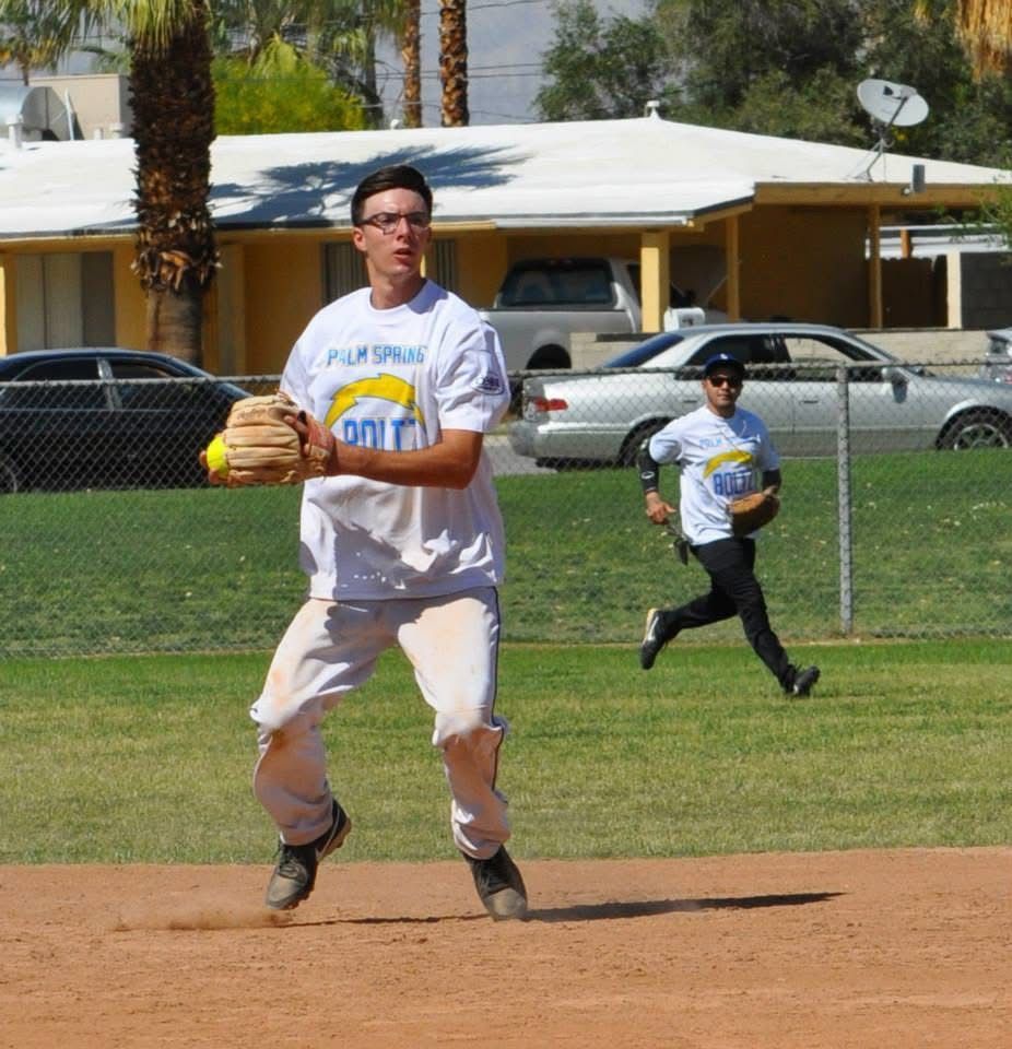 Two boys in white T-shirts run on a baseball field, one holding a ball and wearing a glove.
