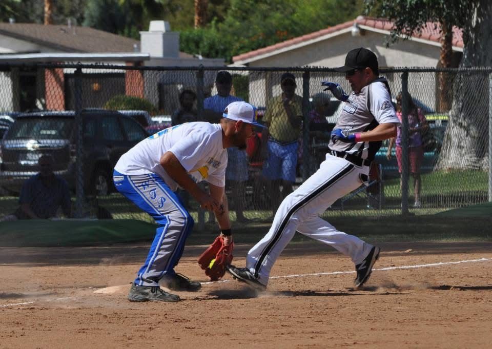 Baseball player sliding into home plate as catcher reaches for the ball on a dirt field