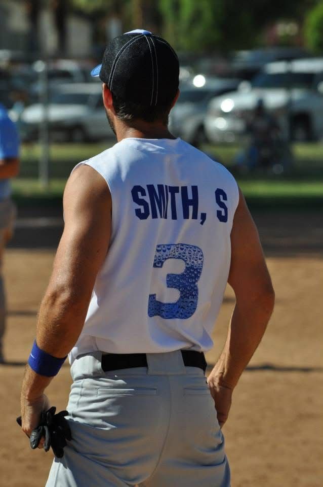 Softball player in white jersey with number 3 and “SMYTH, S” on back, standing on a field.