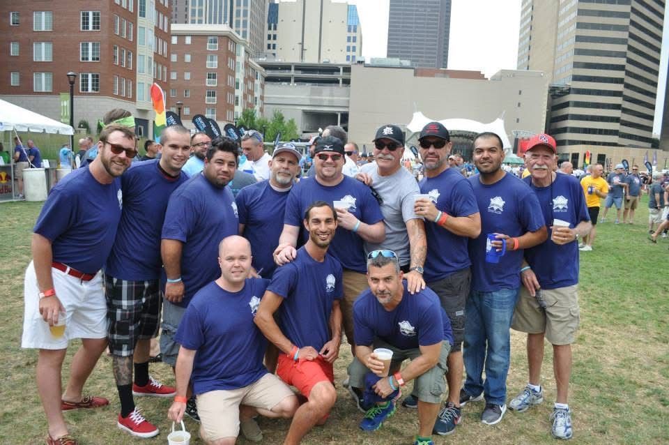Group of people in blue shirts posing together outdoors at a city event, with buildings in the background.