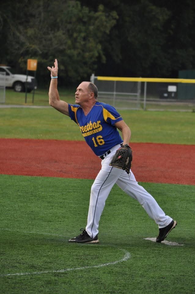Softball player in blue and yellow jersey catches a ball on the field at night