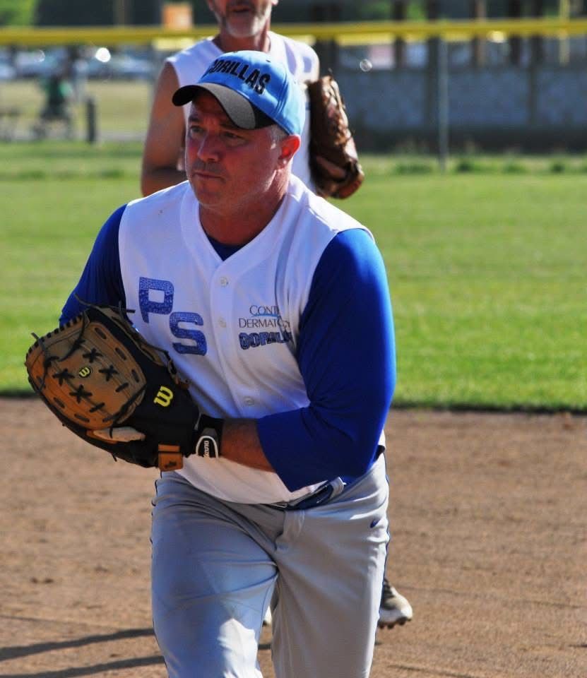 Softball player in blue and white uniform preparing to catch a ball on the field.