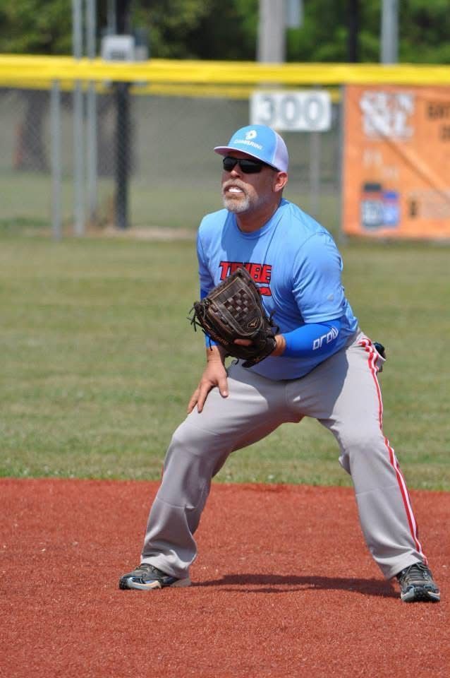 Baseball player in blue jersey and gray pants ready in a fielding stance on the infield.