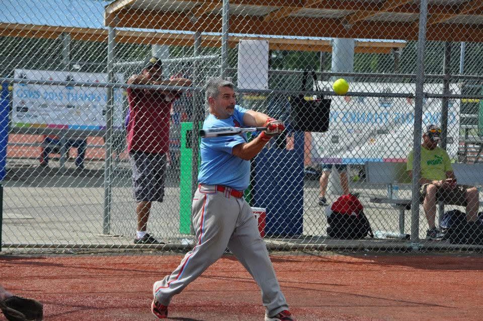 Softball player in blue swings a bat at home plate during a game
