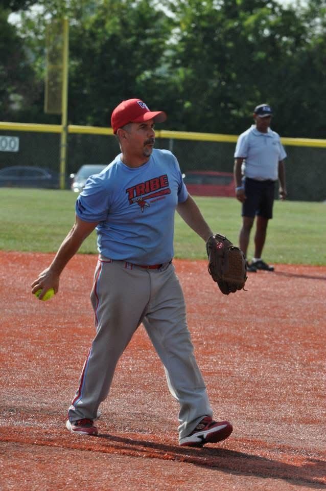 Baseball player in gray uniform and red cap standing on the infield, glove in hand.